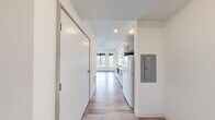 This studio unit at Koz on 420 in Tacoma, Washington, offers a thoughtfully designed single-floor layout that maximizes every square foot of its compact footprint. The space features a clean, modern aesthetic throughout, with light wood-look flooring and crisp white walls that create a bright, airy feel.

The galley-style kitchen is efficiently appointed with two-tone gray and white cabinetry, ample upper and lower storage, a double-basin stainless steel sink, a built-in cooktop, microwave, and a full-size refrigerator — all within easy reach in a streamlined configuration. Recessed lighting illuminates the kitchen and hallway areas.

The main living area benefits from a ceiling fan and a pair of large windows fitted with black roller shades, framing views of the surrounding Tacoma neighborhood and mature trees. The windows draw in generous natural light, enhancing the open feel of the space.

The bathroom is finished in a clean, minimalist style with wood-look tile flooring, a floating vanity with a white countertop, a walk-in shower/tub combination, and chrome fixtures. The entry hallway provides a practical transition from the front door into the living space. Overall, this studio presents a functional, modern living environment suited for efficient urban living in Tacoma.