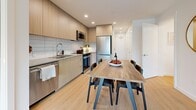 Located at 5828 Granville Street in Vancouver's desirable west side, this thoughtfully designed two-bedroom, two-bathroom unit offers a clean, modern aesthetic across a single floor. Light oak hardwood flooring flows throughout, complemented by crisp white walls and recessed lighting that enhance the sense of brightness and openness.

The kitchen is a standout feature, finished with flat-panel light wood cabinetry extending to the ceiling, a subway tile backsplash, and a full suite of stainless steel appliances including a built-in dishwasher, range, over-the-range microwave, and refrigerator. The kitchen opens directly to the dining area, creating an inviting space for everyday living and entertaining.

A welcoming hallway connects the living areas to the private quarters. The primary bedroom benefits from a large window framing lush greenery, offering a calm, nature-inspired retreat. The second bedroom also features a generous window with neighbourhood views, keeping the space bright and airy.

The two bathrooms are each finished with large-format tiles and light wood vanities. One features a deep soaking tub with an overhead shower, while the other offers a walk-in glass-enclosed shower with floor-to-ceiling tile surround — both maintaining a cohesive, spa-like quality throughout.