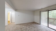 Located at 2024 Sunnyside Dr in Kalamazoo, Michigan, this one-bedroom, one-bathroom unit offers a practical and comfortable single-floor layout. The open-concept living and dining area is carpeted and filled with natural light, thanks to a sliding glass door that leads directly to a private wooden deck overlooking lush greenery — a standout feature that brings the outdoors in. The kitchen is efficiently designed with dark wood cabinetry, laminate countertops, a double stainless steel sink, and white appliances including a refrigerator and electric range. Wood-style flooring in the kitchen adds a warm contrast to the carpeted living spaces. The bedroom is generously sized, featuring a window with a view of the surrounding trees and access to multiple closets, including a louvered bi-fold closet with built-in hanging rods and shelving — providing substantial storage. The unit features four closets in total, offering exceptional storage throughout. The bathroom includes a full tub/shower combo with chrome fixtures and wood-style flooring. Clean white walls and neutral tones throughout give the space a bright, move-in-ready appearance.