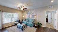 This single-story residence offers a thoughtfully designed open-concept layout that seamlessly connects the main living areas. The living room serves as the heart of the home, featuring dark hardwood-style flooring, a ceiling fan with light fixture, and large windows fitted with blinds and sheer curtains that invite an abundance of natural light. The space flows directly into a dedicated dining area, distinguished by recessed lighting and a pendant light fixture overhead.

The galley-style kitchen is well-equipped with white cabinetry, granite countertops, and a full suite of stainless steel appliances, including a range, microwave, refrigerator, and dishwasher. A kitchen island with granite countertop and bar seating provides additional prep space and casual dining. An elegant arched passage connects the kitchen to the entry foyer.

Two bedrooms offer a quieter retreat, each carpeted and filled with natural light from windows dressed with blinds and sheer curtains. The residence includes two bathrooms, both featuring granite-topped vanities, wood-style flooring, and white cabinetry. One bathroom offers a tub-shower combination, while the other provides a similarly clean and functional layout. Neutral tones throughout create a cohesive and welcoming ambiance.