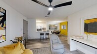 This well-appointed one-bedroom, one-bathroom residence in Union City, GA offers a thoughtfully designed open-concept layout across a single floor. The living, dining, and kitchen areas flow seamlessly together, unified by wood-look plank flooring and a striking bold yellow accent wall in the dining area that adds a vibrant focal point to the space. The living room features a modern ceiling fan, a sliding glass door with vertical blinds that allows natural light to filter in, and ample room for comfortable furnishings. The kitchen is outfitted with crisp white shaker cabinets, marble-look quartz countertops, a subway tile backsplash, stainless steel appliances including a refrigerator and electric range, and a breakfast bar with seating — ideal for casual dining or entertaining. The bedroom is a serene retreat with neutral tones and textured ceiling detail. The full bathroom includes a tub/shower combination, white vanity with marble-look countertop, and black matte hardware accents. A dedicated in-unit laundry room accommodates a full-size washer and dryer, complemented by overhead wire shelving. Storage is well addressed with two closets, including a spacious walk-in closet with multi-tier wire shelving systems.