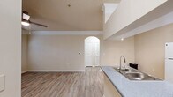 Located at 31324 Deer Trail in Milton, GA, this single-story, one-bedroom, one-bathroom home offers a well-organized layout across a compact yet functional floor plan. The combined kitchen and living area serves as the heart of the home, where light wood-style flooring extends throughout, complemented by neutral beige walls and a ceiling fan with a light fixture. The living room features a tray ceiling with crown molding detailing, a door providing outdoor access, and a window dressed with blinds that frame views of surrounding greenery. The kitchen is efficiently designed with white cabinetry, white appliances including a refrigerator and electric range, a double-basin sink set into a peninsula with grey countertops that overlooks the living area. The bedroom is carpeted and generously sized, featuring multiple windows that invite ample natural light and views of the wooded surroundings. A dedicated closet and an in-unit laundry area with a top-loading washer and overhead shelving add practical convenience. The bathroom includes a full tub-shower combination with tiled surround, wood-style flooring, and a vanity with grey countertop. The space maintains a consistent, clean aesthetic throughout with neutral tones and functional finishes.