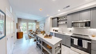 Located at 5919 N Kings Hwy in Alexandria, VA, this thoughtfully designed 3-bedroom, 2-bathroom residence offers a well-appointed single-floor layout that maximizes every inch of its space. The open-concept kitchen and living area serves as the heart of the home, featuring sleek gray cabinetry, a herringbone tile backsplash, white quartz countertops, stainless steel appliances, and a freestanding kitchen island — ideal for both cooking and entertaining. Light wood-style flooring flows seamlessly throughout, lending a clean, cohesive aesthetic. The living room is bright and inviting, anchored by large windows and a glass balcony door that frames lush greenery and pool views, filling the space with natural light. The primary bedroom is a serene retreat with a large window overlooking the outdoors, complemented by a ceiling fan and access to a well-lit bathroom featuring gray vanity cabinetry, LED-lit mirrors, and a dual-sink configuration. A second full bathroom mirrors the same modern finishes. Two closets provide ample storage. The hallways and bathrooms feature light stone-look tile, maintaining a refined, neutral palette throughout. This residence combines contemporary design with functional living in a prime Northern Virginia location.