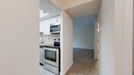 This single-floor residence offers a thoughtfully designed layout that balances modern updates with comfortable living. The kitchen is a standout feature, showcasing white shaker cabinetry, granite countertops, a mosaic tile backsplash, and a full suite of stainless steel appliances, including a range, over-the-range microwave, and refrigerator. Light wood-look flooring runs throughout the main living areas, contributing to a clean, contemporary aesthetic.

The living room is generously proportioned and filled with natural light, courtesy of a large sliding glass door that opens to a balcony overlooking lush, mature greenery. An adjacent dining area benefits from additional windows framing the same tranquil outdoor scenery. A second room also features hardwood-style flooring and its own access to the outdoors through a sliding door, offering further views of the surrounding trees.

The bedrooms are carpeted and well-sized, featuring windows with blinds that provide both natural light and privacy. Multiple doors suggest additional closet or storage access within the bedroom spaces. The bathroom is finished with large-format, neutral-toned tile surrounding a soaking tub, lending a calm, spa-like feel. Throughout the unit, warm neutral wall tones and consistent finishes create a cohesive and inviting atmosphere.