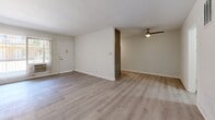 Located at 970 S Menlo Ave in Los Angeles, this 2-bedroom, 1-bathroom unit offers a clean, modern aesthetic across a single floor. Light wood-style flooring runs throughout the space, complementing the crisp white walls and creating a bright, cohesive atmosphere.

The open living area is spacious and airy, with natural light filtering through a large window fitted with vertical blinds. The layout flows directly into the kitchen, which features gray shaker-style cabinetry, white quartz countertops, and a full suite of stainless steel appliances including a gas range, dishwasher, built-in microwave, and refrigerator. A window above the sink adds natural light to the cooking space.

Both bedrooms are well-proportioned and finished with the same light flooring and neutral walls. Each room includes a ceiling fan and ample closet space — one bedroom features a wide sliding-door closet. The primary bedroom offers generous room to accommodate a variety of furniture arrangements.

The bathroom is thoughtfully appointed with a gray vanity, white countertop, framed mirror, and a soaking tub. A frosted window provides natural ventilation and light. A connecting hallway ties all rooms together efficiently, completing this functional and stylishly updated Los Angeles home.