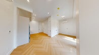 Located at 34-16 38th St in the vibrant Long Island City neighborhood of Queens, this thoughtfully designed two-floor unit offers a seamless blend of modern aesthetics and functional living. Each floor carries an equal footprint, creating a balanced and well-proportioned layout throughout.

Distinctive herringbone-patterned hardwood floors flow continuously across both levels, lending a refined elegance to every room. The open-plan living area is bright and airy, with large windows that invite an abundance of natural light and offer street-level views of the surrounding neighborhood. A wall-mounted split air conditioning unit ensures year-round comfort.

The kitchen is sleek and contemporary, featuring flat-front cabinetry in a soft white finish, under-cabinet lighting, a built-in oven, an induction cooktop, and a stainless steel refrigerator — all set against clean white countertops.

Both bathrooms are finished to a high standard, showcasing large-format beige marble-effect tiles, gold hardware accents, a built-in shower niche, and a soaking tub enclosed by a frameless glass panel — delivering a spa-like atmosphere.

The upper floor provides generously proportioned open spaces with multiple closet doors and recessed lighting, offering flexibility for a variety of uses. A staircase connects the two levels, completing this polished and cohesive urban residence.