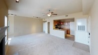 This single-floor residence offers a thoughtfully designed layout that balances open living spaces with comfortable private quarters. The living room serves as the heart of the home, featuring plush wall-to-wall carpeting, a classic fireplace framed by a clean white mantel, and multiple windows that allow natural light to fill the room. A ceiling fan adds both function and style overhead. The living area flows seamlessly into the kitchen, which is separated by a peninsula-style granite countertop island with an undermount double sink. The kitchen is well-equipped with warm wood cabinetry, granite countertops, stainless steel appliances including a range and over-the-range microwave, and tile flooring. Vibrant red pendant lights add a bold design accent above the island, complemented by track lighting overhead. The bedrooms are generously sized with soft carpeting, ceiling fans, and ample natural light from multiple windows. One bedroom features a walk-in closet, while another includes direct access to a hallway. The full bathroom offers a tiled tub-shower combination with a decorative tile accent border, a vanity with a light stone countertop, wood cabinetry, and tile flooring. A dedicated laundry area with washer/dryer hookups and an electrical panel rounds out the practical features of this residence.