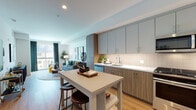 Located at 8809 Washington Blvd in Culver City, California, this single-floor residence offers a thoughtfully designed open layout with modern finishes throughout. Warm wood-tone flooring flows seamlessly across the living spaces, creating a cohesive and inviting atmosphere.

The kitchen is a standout feature, outfitted with two-tone cabinetry in muted sage and natural wood, a classic white subway tile backsplash, and a full suite of stainless steel appliances including a gas range, microwave, dishwasher, and refrigerator. A central island with bar seating provides both additional prep space and a casual dining option.

The living area is bright and welcoming, benefiting from large windows that draw in natural light and offer views to the outdoors. Clean white walls serve as a neutral backdrop, complemented by recessed lighting overhead.

The bedroom is a comfortable retreat featuring a large window with access to a private balcony, allowing for an abundance of natural light. Built-in shelving adds a practical yet stylish storage solution.

The bathroom is finished with large-format neutral floor tiles, warm wood cabinetry with a white countertop, and a full tub-shower combination framed by subtly textured wall tile. The overall design of this residence balances contemporary style with functional, day-to-day livability.