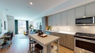 Located at 8809 Washington Blvd in Culver City, California, this single-floor residence offers a thoughtfully designed open layout with modern finishes throughout. Warm wood-tone flooring flows seamlessly across the living spaces, creating a cohesive and inviting atmosphere.

The kitchen is a standout feature, outfitted with two-tone cabinetry in muted sage and natural wood, a classic white subway tile backsplash, and a full suite of stainless steel appliances including a gas range, microwave, dishwasher, and refrigerator. A central island with bar seating provides both additional prep space and a casual dining option.

The living area is bright and welcoming, benefiting from large windows that draw in natural light and offer views to the outdoors. Clean white walls serve as a neutral backdrop, complemented by recessed lighting overhead.

The bedroom is a comfortable retreat featuring a large window with access to a private balcony, allowing for an abundance of natural light. Built-in shelving adds a practical yet stylish storage solution.

The bathroom is finished with large-format neutral floor tiles, warm wood cabinetry with a white countertop, and a full tub-shower combination framed by subtly textured wall tile. The overall design of this residence balances contemporary style with functional, day-to-day livability.