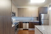 Located at 9300 Lottsford Rd in Upper Marlboro, MD, this well-appointed 2-bedroom, 2-bathroom residence offers a thoughtfully designed single-floor layout with a generous overall footprint. The open-concept kitchen and living area serves as the heart of the home, showcasing rich hardwood flooring, two-tone cabinetry in light and dark finishes, granite countertops, a central island with pendant lighting, and a full suite of stainless steel appliances including a refrigerator, range, microwave, and dishwasher. The living room benefits from natural light through a large window with access to a private balcony. Both bathrooms are finished with tiled tub-shower combinations featuring curved curtain rods and brushed nickel fixtures, set on stone-look tile flooring. The primary bedroom is carpeted and generously sized, offering direct access to a walk-in closet with built-in wire shelving and a private en-suite bathroom with dark wood vanity cabinetry and granite counters. The second bedroom features durable hardwood-style flooring and a neutral palette. A second walk-in closet provides additional storage. Clean lines, neutral tones, and modern finishes create a cohesive and comfortable living environment throughout.
