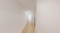 Located in Calgary, AB, this thoughtfully designed unit offers three bedrooms, two bathrooms, and in-suite laundry across a single floor. The open-concept kitchen and living area serves as the heart of the home, featuring white cabinetry, a subway tile backsplash, stainless steel appliances including a microwave, range, and refrigerator, and a peninsula with an undermount sink — all illuminated by track lighting and a large window overlooking the street. Light wood-tone flooring runs consistently throughout, lending warmth and visual continuity to every room. The bedrooms are bright and well-proportioned, each equipped with sliding or swing-out closets and windows that bring in natural light and urban views. The primary bedroom offers a cozy, functional layout with a dedicated closet. Both bathrooms are finished in a clean, modern style; one features a frameless sliding glass shower enclosure, large-format white wall tiles, an undermount vanity sink with open shelving, and wood-tone flooring. A central hallway connects the bedrooms and bathrooms efficiently, finished in crisp white walls and matching flooring. The dedicated laundry room houses a stacked washer and dryer unit with additional storage space. The overall aesthetic is clean, bright, and contemporary throughout.