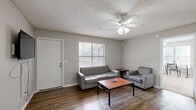 Located in Tallahassee, FL 32303, this single-story residence offers four bedrooms and four bathrooms, providing ample space and privacy for all occupants. The combined kitchen and living room area forms the heart of the home. The kitchen features light wood cabinetry, white appliances including a refrigerator and electric range, a skylight for added brightness, and a breakfast bar with seating — ideal for casual dining. The living room is finished with wood-style flooring, a ceiling fan, and a window that brings in natural light. Adjacent to the kitchen is a dedicated dining area with wall sconce lighting, creating a cozy setting for meals. The bedrooms are carpeted and offer a clean, neutral palette, with sliding closet doors providing convenient storage. The four bathrooms are consistently appointed with tile flooring, extended vanity countertops, mirrored medicine cabinets, and shower-tub combinations. Select bathrooms also include built-in shelving for additional storage. A dedicated laundry room adds everyday convenience. The textured ceilings and neutral wall tones found throughout create a cohesive and functional living environment suited for a variety of lifestyles.