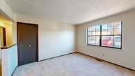 Located at 2849 Colony Wood Cir SW in Canton, Ohio, this one-bedroom, one-bathroom unit offers a practical and efficient single-floor layout. The living room features light carpeting, neutral walls, a textured ceiling, and a large multi-pane window that invites natural light and exterior views. The kitchen is equipped with warm wood cabinetry, a white tile backsplash, light wood-style vinyl flooring, a double stainless steel sink, a gas range, and a refrigerator. A ceiling fan overhead adds comfort to the kitchen and adjacent dining area. The bedroom provides a comfortable, carpeted retreat with a wide sliding-door closet for generous storage, an additional door for further access, and a window that brings in natural light. The bathroom includes a full tub-shower combo with clean white surround panels, complemented by a towel bar and tile flooring. Additional spaces include a hallway, a utility room, and two closets throughout the unit, maximizing storage and organization. Dark-toned door and window trim throughout provides a consistent, grounded aesthetic against the light-colored walls and flooring.