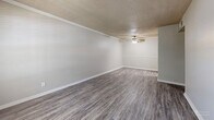 Located at 251 Eisenhower Dr in Biloxi, Mississippi, this single-floor, 2-bedroom, 2-bathroom residence offers a practical and well-organized layout. The living room greets you at the entrance with durable vinyl plank flooring in a neutral gray tone, a textured ceiling, crown molding, a ceiling fan, and a window that invites natural light and views of the surrounding greenery. The galley-style kitchen is efficiently designed with white cabinetry, light countertops, a stainless steel sink, and black appliances including a refrigerator and electric range. Both bedrooms feature plush carpeting, ceiling fans, and windows that provide natural light and outdoor views, creating comfortable and restful spaces. The primary bedroom offers a generous footprint with ample room for furnishings. The two bathrooms are clean and functional — one includes a vanity with white cabinetry, a large mirror, and warm-toned countertops, while the other features a full tub-shower combination with built-in shelving. A dedicated closet and hallway complete the layout. The overall design is neutral and move-in ready, with consistent finishes throughout that create a cohesive, low-maintenance living environment.