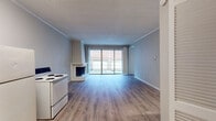 This single-story space is designed with a practical, open layout highlighted by light-toned laminate wood flooring that flows consistently throughout. The main living area serves as the focal point of the unit, anchored by a white brick fireplace with a prominent chimney surround and flanked by built-in open shelving — a standout architectural detail that adds both character and storage functionality. Large sliding glass doors flood the living area with natural light and provide direct access to a private balcony, offering views of the surrounding exterior. Crown molding and a textured ceiling add subtle definition to the space.

The kitchen features granite countertops, a subway tile backsplash, gray cabinetry, an undermount sink, a dishwasher, and an electric range, combining practicality with updated finishes. The bedrooms are comfortably sized, with one offering direct access to a bathroom and another featuring a ceiling fan and window with natural light. Two bathrooms serve the unit; one includes a tiled tub-shower combination, while the second features a clean, straightforward shower-tub setup. The neutral color palette and consistent flooring throughout create a cohesive, move-in-ready atmosphere.