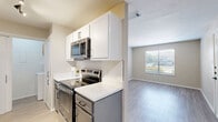 This single-floor, 2-bedroom, 2-bathroom residence offers a thoughtfully designed layout that makes efficient use of its space. The open-concept kitchen and living area serves as the heart of the home, where a galley-style kitchen features two-tone cabinetry with crisp white upper cabinets and slate gray lower cabinets, complemented by light quartz countertops, stainless steel appliances, and light wood-look flooring. The kitchen flows seamlessly into the living area, which is carpeted and bathed in natural light through a large sliding glass door fitted with vertical blinds that open to the outdoors. The primary bedroom is generously sized, also carpeted, and includes a sliding glass door for additional natural light and outdoor access. The second bedroom features light wood-look flooring and a bright window with views of the surrounding greenery. Both bathrooms are clean and functional, with tub-shower combinations and light flooring. A dedicated in-unit laundry area adds everyday convenience. Two closets provide ample storage throughout. Neutral-toned walls, consistent light flooring, and a cohesive modern palette give the entire space a bright, clean, and move-in-ready feel.