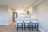 Located at 1547 Mississauga Valley Blvd in Mississauga, Ontario, this well-appointed 3-bedroom, 1-bathroom unit offers a bright and efficiently designed single-floor layout. The open-concept kitchen and living area serves as the heart of the home, featuring white cabinetry, a subway tile backsplash, stainless steel appliances, and a peninsula island with bar seating — ideal for casual dining and entertaining. Light hardwood-style flooring runs throughout, contributing to a clean, contemporary aesthetic. The living area is bathed in natural light and offers sliding glass door access to a private balcony overlooking a lush, tree-lined neighbourhood. Each of the three bedrooms is finished with the same light flooring and features wide windows fitted with roller blinds, offering views of the surrounding greenery and cityscape. Baseboard heating units are present beneath the windows in each bedroom. The primary bedroom provides a comfortable amount of space. The full bathroom is finished in crisp white tiling and features a soaker tub with a polished chrome fixture. A dedicated closet adds practical storage. The overall ambiance is modern, light-filled, and move-in ready, with a neutral colour palette throughout.