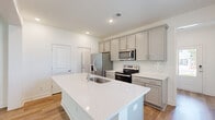 Located in Johns Island, SC, this two-story, 3-bedroom, 3-bathroom home offers a well-designed layout spread across two comfortable floors. The main level features an open-concept living and kitchen area highlighted by warm luxury vinyl plank flooring that flows throughout. The kitchen is a standout, boasting a large quartz-topped island with an undermount sink, gray shaker-style cabinetry, a classic subway tile backsplash, and a full suite of stainless steel appliances. Natural light pours in through multiple windows dressed with white blinds, creating a bright and airy atmosphere. The spacious living room includes a ceiling fan and connects seamlessly to the kitchen, making it an ideal space for everyday living. A staircase leads to the upper level, where the generously sized primary bedroom is accompanied by a well-appointed en suite bathroom featuring a tiled walk-in shower with glass doors, a quartz vanity, and hardwood-style flooring. Two additional bedrooms on the upper floor each offer closet storage and natural light. Three full bathrooms with clean, modern finishes serve all three bedrooms. The home also includes a dedicated entrance, multiple hallways for easy circulation, and a closet for additional storage throughout.