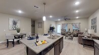 Located at 605 E Fish Creek Rd in Grand Prairie, Texas, this single-story residence offers a well-designed, open-concept layout with modern finishes throughout. The kitchen is a standout feature, equipped with rich dark cabinetry extending to the upper walls, granite-style countertops, stainless steel appliances including a refrigerator, range, and microwave, and light wood-look flooring that flows seamlessly into the living and dining areas. A central kitchen island with a double stainless steel sink and pendant lighting serves as both a functional workspace and a natural gathering point. The open living area provides a comfortable, airy atmosphere, complemented by a ceiling fan, recessed lighting, and windows that invite natural light. The bedrooms are carpeted and feature ceiling fans, windows with blinds and curtains, and ample space. Two bathrooms are present: one full bathroom with a soaking tub and shower combination, dark vanity cabinetry, and granite-style countertops, and a second bathroom featuring a single vanity with matching dark cabinetry and storage above. Neutral wall tones and consistent design elements throughout create a cohesive, contemporary aesthetic well-suited for comfortable everyday living.