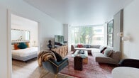 Located at 1001 Minor Avenue in Seattle's First Hill neighborhood, this thoughtfully designed unit offers a seamless blend of modern aesthetics and functional living. The open-concept living area is anchored by a dramatic wall of floor-to-ceiling windows that frame lush tree canopy views, flooding the space with natural light. An exposed concrete accent column adds an industrial touch, complementing the clean white walls and warm hardwood-style flooring that flows throughout.

The kitchen is a standout, featuring a generous island with seating for several, sleek grey cabinetry, dark stone countertops, a matte black faucet, and a full suite of stainless steel appliances. The layout is ideal for both everyday cooking and entertaining.

The bedroom is a serene retreat with a large window overlooking greenery, a walk-in closet with built-in organization, and ample room for a queen or king bed. The full bathroom is finished with large-format tile flooring, a floating vanity with an undermount sink, and a tub-shower combination.

Completing the unit is an in-unit stacked washer and dryer, adding everyday convenience. The overall ambiance is contemporary and polished, with industrial accents and abundant natural light defining the character of the space.