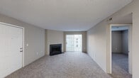 Located on Cape Landing Circle in Myrtle Beach, South Carolina, this single-floor residence offers a practical and comfortable layout with a neutral color palette throughout. The spacious living room serves as the focal point of the home, featuring plush wall-to-wall carpeting, a classic fireplace with a dark surround, and a large sliding glass door that fills the space with natural light and provides access to an outdoor area. Textured ceilings are present throughout the living spaces, adding a traditional character to the interior. The galley-style kitchen is efficiently designed with ample white cabinetry, white appliances including an electric range and refrigerator, light countertops, and wood-look vinyl flooring that extends into the adjacent areas. The bedroom is generously sized with soft carpeting, a sliding glass door allowing additional natural light, and access to a walk-in closet equipped with wire shelving for organized storage. The bathroom features wood-look vinyl flooring, a tub-shower combination, and a vanity, all finished in neutral tones that complement the rest of the home. The overall ambiance is clean, understated, and move-in ready, making it a solid residential option in the Myrtle Beach area.