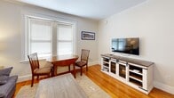Located at 11 Shepley St in the heart of Portland, Maine, this efficient one-bedroom, one-bathroom residence offers a well-organized floor plan across a single level. Warm hardwood flooring and crown molding run throughout, lending a classic New England character to the space.

The living room serves as the central gathering area, featuring a window with blinds that allows natural light to brighten the room, a ceiling fan, and enough space for a sofa and dining set. A framed nautical print adds a nod to Portland's maritime heritage.

The bedroom is a cozy, well-proportioned retreat with its own window providing natural light, a traditional cast-iron radiator for warmth, and a ceiling fan overhead. The neutral walls and hardwood floors maintain a calm, restful ambiance.

The kitchen is efficiently designed with white upper cabinetry, a white subway tile backsplash, stainless steel countertops, a deep single-basin sink with a modern chrome faucet, and a compact refrigerator — providing all essential functionality in a thoughtfully arranged space.

The bathroom is finished in a clean, all-white palette with subway tile walls, stone-look tile flooring, and a modern toilet, creating a crisp and tidy atmosphere. Connecting hallways link the rooms seamlessly, completing this practical and charming urban residence.