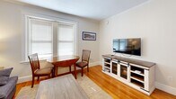 Located at 11 Shepley St in the heart of Portland, Maine, this efficient one-bedroom, one-bathroom residence offers a well-organized floor plan across a single level. Warm hardwood flooring and crown molding run throughout, lending a classic New England character to the space.

The living room serves as the central gathering area, featuring a window with blinds that allows natural light to brighten the room, a ceiling fan, and enough space for a sofa and dining set. A framed nautical print adds a nod to Portland's maritime heritage.

The bedroom is a cozy, well-proportioned retreat with its own window providing natural light, a traditional cast-iron radiator for warmth, and a ceiling fan overhead. The neutral walls and hardwood floors maintain a calm, restful ambiance.

The kitchen is efficiently designed with white upper cabinetry, a white subway tile backsplash, stainless steel countertops, a deep single-basin sink with a modern chrome faucet, and a compact refrigerator — providing all essential functionality in a thoughtfully arranged space.

The bathroom is finished in a clean, all-white palette with subway tile walls, stone-look tile flooring, and a modern toilet, creating a crisp and tidy atmosphere. Connecting hallways link the rooms seamlessly, completing this practical and charming urban residence.