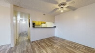 This single-floor residence offers a functional and comfortable layout with a clean, neutral aesthetic throughout. The living area features light wood-look flooring, a ceiling fan with integrated lighting, and a sliding glass door fitted with vertical blinds that allows natural light to fill the space. A half-wall pass-through connects the living area to the kitchen, creating an open feel while maintaining defined zones.

The galley-style kitchen is well-equipped with warm wood cabinetry, dark speckled countertops, and a full suite of appliances including a stove, refrigerator, dishwasher, and built-in microwave. The layout maximizes storage and counter space efficiently along both walls.

The bedrooms are carpeted for comfort and each features a ceiling fan with lighting and a built-in closet with hanging rods. One bedroom includes a sliding glass door offering natural light and outdoor access, while another features a dedicated entry door with closet storage nearby.

The bathrooms are appointed with wood vanity cabinetry, dark speckled countertops, integrated sinks, and large mirrors. Natural light enters through window openings dressed with vertical blinds, enhancing the brightness of each vanity area. Textured ceilings are consistent throughout the residence, contributing to a cohesive interior character.