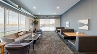 Located at 7412 E 26th St in Sioux Falls, SD, this thoughtfully designed amenity floor spans a generous single level, offering a diverse range of spaces tailored for fitness, recreation, and relaxation. The entry welcomes visitors with a sleek reception desk, light wood accent wall, and polished tile flooring that transitions seamlessly into carpeted hallways adorned with curated artwork and accent furnishings.

The fitness center is a standout feature, offering an expansive, well-lit workout space equipped with a full row of treadmills and elliptical machines, free weights, kettlebells, medicine balls, and weight benches. Floor-to-ceiling mirrors line one wall, and natural light filters in through multiple windows. An adjacent golf simulator room provides a dedicated space with a projector, screen, and synthetic turf hitting mat for an immersive indoor experience.

The lounge and social areas are elegantly appointed with contemporary furniture, patterned carpeting, and exposed metallic ductwork that lends an urban-industrial character. Large windows throughout flood these spaces with natural light and offer exterior views. A game room features a pool table and foosball table alongside comfortable seating, creating an ideal setting for casual gatherings. Throughout, the design balances modern aesthetics with functional, community-oriented living.