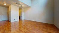 This two-story residence offers a thoughtfully designed layout with standout architectural details across both levels. The main living area immediately impresses with soaring double-height ceilings and large windows that flood the space with natural light, while warm hardwood flooring extends throughout the open floor plan. A sleek staircase with a black metal railing connects the two floors, adding a modern design element to the space.

The kitchen is well-appointed with rich wood cabinetry, granite countertops, and a full suite of stainless steel appliances including a refrigerator, range, and over-the-range microwave. The extended granite breakfast bar provides additional prep and dining space, all set atop gleaming hardwood floors.

The bathroom features a functional and clean design with dark vinyl tile flooring, a warm wood vanity topped with granite, a dedicated toilet area, and a full bathtub with shower, all finished with chrome fixtures.

Upstairs, the loft-style second level offers a generously sized open room with plush carpeting and windows overlooking greenery, making it a versatile space suited for a bedroom, office, or additional living area. Track lighting on the upper level provides flexible illumination. Together, both floors create a well-balanced, functional living space with quality finishes throughout.
