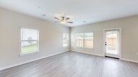 Located at 7711 Longmire Rd in Conroe, Texas, this two-story home offers a thoughtfully designed layout spread across two floors. The main level opens into a combined kitchen and living area, where the kitchen stands out with tall white cabinetry, a white subway tile backsplash, dark granite countertops, stainless steel appliances, and a central island with a sink. The living room benefits from multiple windows fitted with blinds, a ceiling fan, and light-toned luxury vinyl plank flooring that flows throughout the home, creating a bright and cohesive feel. A hallway connects the main areas seamlessly, with recessed pendant lighting guiding the way. The second floor hosts the three bedrooms, each featuring ceiling fans, generous natural light from large windows, and the same durable flooring. The spacious primary bedroom includes its own walk-in closet outfitted with built-in shelving and hanging rods for ample storage. The three bathrooms are clean and functional, with white vanities, granite countertops, dark hardware accents, and tub-shower combinations. A dedicated laundry room with a full-size washer and dryer and overhead shelving adds everyday convenience. The home presents a clean, modern aesthetic throughout with neutral tones and quality finishes.