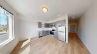 Located at 3725 N 27th St in Tacoma, Washington, this single-floor unit offers a clean, modern aesthetic with a thoughtfully designed open-concept layout. Light wood-style flooring runs consistently throughout the space, creating a cohesive and bright interior.

The kitchen is a standout feature, outfitted with sleek gray flat-panel cabinetry that extends to the ceiling for ample storage. White countertops provide a crisp contrast, while a full suite of stainless steel appliances — including a refrigerator, electric range, built-in microwave, and dishwasher — delivers a well-equipped cooking space. Recessed lighting and a flush-mount ceiling fixture keep the area well-lit.

The open living area flows naturally from the kitchen, offering a flexible and spacious environment bathed in natural light. The minimalist white walls and clean lines contribute to a contemporary, airy ambiance throughout.

The bathroom is efficiently designed with a combination tub and shower, a streamlined vanity with gray cabinetry, and a wall-mounted medicine cabinet. A notable convenience is the stacked in-unit washer and dryer, located just off the bathroom. The bedroom provides a quiet, private retreat with warm wood-tone flooring and a sliding closet door, completing this well-appointed, move-in ready space.