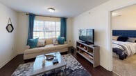 This single-floor, three-bedroom, three-bathroom residence offers a thoughtfully organized layout designed for comfortable everyday living. The living room serves as the central gathering space, featuring rich dark hardwood-style flooring, large windows with teal curtains that invite ample natural light, and a welcoming, open feel. Adjacent to the living area, the kitchen is well-equipped with warm honey-toned cabinetry, granite-style countertops, dark hardwood-style floors, and a full suite of black appliances including a refrigerator, range, and over-the-range microwave.

Each of the three bedrooms is carpeted for comfort and includes windows that bring in natural light. The primary bedroom features a walk-in closet, while another bedroom showcases a distinctive reclaimed wood headboard wall accent. The third bedroom offers a clean, versatile space suitable for a variety of uses.

The three bathrooms are finished with dark hardwood-style flooring and warm wood vanities with white countertops. One bathroom includes a soaking tub with grab bars, while the others feature shower-tub combinations, providing practical options for all residents. Together, these spaces create a cohesive, functional home with consistent finishes throughout.
