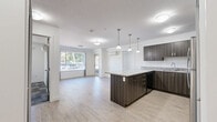 Located at 2699 Peatt Road in Langford, BC, this well-appointed two-bedroom, two-bathroom unit offers a thoughtfully designed single-floor layout with a clean, modern aesthetic throughout. The kitchen serves as a functional centerpiece, showcasing dark wood-toned cabinetry, a granite-topped island ideal for casual dining or meal preparation, pendant lighting, and stainless steel appliances including a full-size refrigerator and range. Light wood-style vinyl flooring runs through the main living and kitchen areas, lending warmth and continuity to the space. Both bathrooms are finished with granite countertops, undermount sinks, and contemporary brushed nickel fixtures, reflecting a consistent attention to detail. The bedrooms feature patterned carpet tile flooring and are equipped with grey shaker-style closet doors providing ample storage. The secondary bedroom benefits from a window that invites natural light and offers outdoor views, while a wall-mounted mini-split unit ensures year-round climate comfort. The hallway is lined with grey panelled doors that contribute to the cohesive, modern design language carried throughout the unit. A dedicated closet adds further storage convenience. Overall, the space presents a clean, neutral palette well-suited for comfortable everyday living.