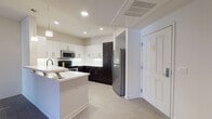 Located at 9800 Mira Lee Way in the Mira Mesa neighborhood of San Diego, California, this single-floor unit offers a well-designed layout with a clean, modern aesthetic throughout. The kitchen is a standout feature, showcasing a two-tone design with crisp white upper cabinets and rich dark espresso lower cabinets, all complemented by white countertops and stainless steel appliances including a refrigerator, range, and microwave. A kitchen island with pendant lighting provides additional workspace and opens seamlessly to the living area. The living room is generously proportioned, featuring neutral carpet flooring and recessed lighting, with an open sightline to the kitchen that creates an inviting, connected atmosphere. Multiple bedrooms offer plush carpeting, natural light through windows with exterior views, and clean white walls that provide a versatile canvas. Two full bathrooms mirror the kitchen's design sensibility, featuring dark vanity cabinetry, white countertops, large mirrors, tile flooring in a light gray tone, and full shower-tub combinations. The overall palette of whites, grays, and dark espresso accents gives the space a cohesive, contemporary character throughout.