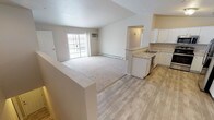 Located at 2243–2249 Commercial Dr in Waupaca, Wisconsin, this single-floor unit offers a clean, functional layout with a neutral color palette throughout. The open-concept design connects the kitchen and living areas seamlessly, creating a spacious, airy feel that is well-suited for everyday living.

The kitchen is well-appointed with white cabinetry, light granite-style countertops, a double stainless steel sink, and a full suite of stainless steel appliances including a refrigerator, range with microwave hood, and dishwasher. Wood-look plank flooring runs through the kitchen and adjoining dining area, adding warmth and durability. A ceiling fan overhead enhances comfort in the open living space.

The living room features plush carpeting, a sliding glass patio door that brings in natural light, and a wall-unit air conditioner. Baseboard heating is present throughout the unit for consistent warmth. The bedrooms are carpeted and include natural light from windows with exterior views, and at least one features a sliding closet with built-in shelving.

The bathrooms are finished with wood-look flooring, granite-style vanity tops, white cabinetry, and include both a walk-in shower and additional facilities. The overall ambiance is bright, neutral, and move-in ready.