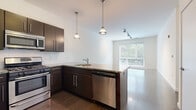 Located on Chapel Street in the heart of New Haven, CT, this single-floor unit offers a clean, contemporary design with a thoughtful layout. The open-concept kitchen is a standout feature, equipped with stainless steel appliances including a gas range, microwave, dishwasher, and refrigerator. Rich dark-toned cabinetry is paired with granite countertops and a subway tile backsplash, while pendant lighting adds a refined touch above the kitchen peninsula. The kitchen flows naturally into the living area, which benefits from large windows that invite abundant natural light and provide views of the surrounding greenery. Hardwood-style flooring runs throughout the main living and kitchen areas, adding warmth and continuity to the space. The bedrooms are carpeted for comfort, with neutral tones and large windows that frame outdoor views, creating bright and airy retreats. The bathroom features a modern floating vanity with a wall-mounted mirror, tile flooring, and a clean, minimalist aesthetic. The overall ambiance of the unit is modern and functional, with a neutral color palette that provides a versatile backdrop for any interior style. Situated on Chapel Street, the location offers convenient access to New Haven's vibrant dining, cultural, and academic amenities.