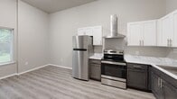 Located at 2601 Carpenter Station Rd in Wilmington, Delaware, this two-floor residence offers a clean, modern aesthetic with thoughtfully updated finishes throughout. The main level features light wood-style luxury vinyl plank flooring that flows seamlessly through the entry, living area, and kitchen. A staircase with a dark metal railing connects the floors, with a utility panel conveniently situated nearby. Large sliding glass doors with vertical blinds flood the living area with natural light and offer views of the greenery outside.

The kitchen is well-appointed with two-tone cabinetry — crisp white upper cabinets paired with dark lower cabinets — complemented by marble-style countertops, stainless steel appliances including a full-size refrigerator and electric range, and a wall-mounted ventilation hood. The layout provides ample counter and storage space, making it both functional and visually appealing.

Upstairs, the bedrooms feature plush gray carpeting and bright windows that invite natural light. The bathroom is finished with wood-style LVP flooring, a white vanity, a full bathtub, and clean, neutral walls. Throughout the space, a consistent neutral color palette of soft grays and whites creates a calm, cohesive ambiance that is move-in ready.