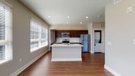 Located at 114 E Fifth Ave in Columbus, Ohio, this single-floor residence offers a thoughtfully designed open-concept layout that seamlessly connects the kitchen and living area. The kitchen is a standout feature, showcasing rich dark-stained cabinetry, white quartz countertops, a central island with an undermount sink and integrated dishwasher, and a full suite of stainless steel appliances including a range, microwave, and refrigerator. A white subway tile backsplash adds a clean, contemporary touch, while recessed lighting and large windows flood the space with natural light. The hardwood-style flooring throughout the main living areas adds warmth and continuity, flowing from the kitchen into the open living space. The bedroom features plush carpeting and a generously sized window with horizontal blinds, offering views of the surrounding neighborhood. The bathroom is finished with a dark vanity complementing the white countertop, wood-look flooring, and clean neutral walls. A dedicated in-unit laundry area with a stacked washer and dryer provides added convenience. Neutral wall tones and recessed lighting throughout create a bright, modern ambiance suited for everyday living.