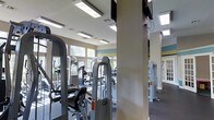 This fitness center is a thoughtfully designed single-floor space built to support a comprehensive workout routine. The room is outfitted with a wide selection of strength training machines, including cable and resistance equipment, arranged throughout the floor to allow comfortable movement between stations. Structural columns are integrated into the layout, adding an architectural element while subtly defining workout zones within the open space. Large windows along the perimeter walls flood the interior with natural light, creating a bright and energizing atmosphere. The ceiling features both recessed fluorescent lighting and what appears to be skylights, ensuring consistent illumination throughout the day. Mounted flat-screen televisions are positioned at convenient viewing angles, allowing members to stay entertained during their sessions. The walls are finished in neutral tones accented with subtle horizontal color bands, lending the space a clean and modern aesthetic. The dark flooring provides a practical, durable surface suited to heavy equipment and high-traffic use. Overall, the fitness center balances functionality with a welcoming environment, making it a well-rounded facility for a variety of fitness needs.