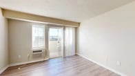 Located in Spokane Valley, WA, this three-bedroom, one-bathroom unit offers a well-organized single-floor layout designed for comfortable everyday living. The living room features light wood-style flooring, a textured ceiling, and a sliding glass door that opens to a private balcony with outdoor views — filling the space with natural light. A wall-unit HVAC system provides climate control directly in the living area.

The kitchen is efficiently designed with warm honey-toned wood cabinetry, light countertops, a peninsula breakfast bar, and white appliances including an electric range and refrigerator. The wood-style flooring continues throughout, and overhead lighting keeps the space bright and functional.

The three bedrooms are carpeted for comfort, each featuring windows with blinds that bring in natural light. Closets with sliding doors provide ample storage, and the layout of the rooms allows for flexible use of space. One bedroom also features a built-in electrical panel.

The full bathroom includes a tub-shower combination, a single-sink vanity with a large mirror, and neutral toned finishes throughout. Clean lines and light colors give the bathroom a simple, functional aesthetic.

Overall, the unit presents a neutral, move-in-ready palette with consistent finishes throughout, making it a practical and comfortable home in Spokane Valley.