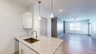 Located at 6386 Transit Rd in Depew, NY, this well-appointed 1-bedroom, 1-bathroom single-floor residence offers a thoughtfully designed open-concept layout with modern finishes throughout. Light-toned hardwood-style flooring flows through the main living areas, complemented by crisp white walls and abundant natural light.

The kitchen serves as a central highlight, featuring granite countertops, white shaker-style cabinetry, a classic subway tile backsplash, and a full suite of stainless steel appliances including a refrigerator, range, microwave, and dishwasher. A peninsula with a undermount sink and stylish pendant lighting connects the kitchen seamlessly to the living area, which offers generous space, a ceiling fan, and a glass door providing additional natural light.

The bedroom is a comfortable retreat with plush carpeting, a window with blinds, and a ceiling-mounted ventilation fixture. An adjacent walk-in closet provides multi-tier wire shelving for ample storage. The bathroom is finished with granite-topped white vanity cabinetry, a full tub/shower combo, brushed nickel fixtures, and wood-look flooring. A hallway connects the rooms efficiently, completing this clean, move-in-ready residence.