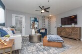Located at 2350 Windward Ln in Gainesville, Georgia, this single-story residence offers a thoughtfully designed layout with a cohesive contemporary aesthetic throughout. The living room serves as the heart of the home, featuring wood-look flooring, a ceiling fan, and a bold navy accent wall that anchors the space with striking visual depth. Natural light filters in through multiple windows dressed with patterned curtains, creating an inviting atmosphere. An adjacent dining area provides an intimate setting, complete with a pendant chandelier overhead and wainscoting detail along the walls. The galley-style kitchen is well-equipped with stainless steel appliances, gray shaker-style cabinetry, granite countertops, a subway tile backsplash, and wood-look flooring, with a laundry area conveniently accessible just beyond. The bedrooms offer plush carpeting, ceiling fans, and window treatments that balance light control with warmth. One bedroom features a soothing teal accent wall for added character. The bathrooms are finished with granite-topped vanities and tub-shower combinations, with wood-look flooring tying the design together. Throughout, a neutral gray palette with warm accent tones creates a cohesive, modern living environment.