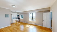 Located on Kingsley Street in Asbury Park, NJ, this single-floor unit offers a clean, functional layout with consistent design details throughout. The open living area is finished with warm-toned hardwood flooring that extends through the main living space, bedroom, and kitchen area, creating a cohesive and inviting atmosphere. Neutral gray walls complement the light-colored floors, providing a versatile backdrop throughout the unit.

The kitchen is efficiently designed with white cabinetry, stainless steel appliances including a gas range, microwave, dishwasher, and refrigerator, along with a double-basin sink. Multiple windows in the main living area allow generous natural light to fill the space and offer views of the surrounding Asbury Park neighborhood. Baseboard heating units run along the exterior walls, providing practical climate control.

The bedroom is a well-proportioned room featuring a large closet with built-in shelving and rod, a window with neighborhood views, and direct access to the bathroom. The bathroom stands out with its decorative mosaic tile accent wall surrounding the tub-shower combination, complemented by neutral stone-toned wall tiles, adding a distinctive design element to the space.