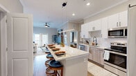 Located at 4090 Rio Vista Dr in Colorado Springs, CO, this well-appointed 2-bedroom, 2-bathroom residence offers a thoughtfully designed single-floor layout with modern finishes throughout. The open-concept kitchen is a standout feature, boasting white upper cabinetry paired with light wood lower cabinets, a subway tile backsplash, stainless steel appliances, and a generous granite-topped island with bar seating — ideal for both everyday dining and entertaining. Crown molding and recessed lighting add a refined touch to the shared living and dining areas. The living room exudes warmth with a tile-surround fireplace, ceiling fan, and French doors that invite natural light and outdoor access. Both bedrooms are bright and comfortable, featuring large windows with blinds and dedicated closets equipped with wire shelving systems. The primary bedroom includes its own en-suite bathroom with a marble-topped vanity, wood-toned cabinetry, matte black fixtures, a glass-enclosed shower, and direct access to a walk-in closet. The second bathroom mirrors the same quality finishes. Durable wood-look flooring flows throughout the main living areas, complementing the home's contemporary aesthetic. This residence offers a cohesive blend of style, function, and comfort in every room.