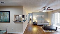 Located on E Old River Rd in Jacksonville, FL, this well-appointed single-story residence offers a thoughtfully designed open-concept layout that promotes a seamless flow throughout. Rich hardwood-style flooring runs through the main living areas, complemented by neutral warm tones and soft blue accent walls that create a calm, inviting atmosphere. The living room features a ceiling fan and a large sliding glass door that floods the space with natural light. Adjacent to it, the dining area connects directly to the kitchen via a convenient pass-through counter. The kitchen is outfitted with dark espresso cabinetry, granite-style countertops, stainless steel appliances, and ample storage. A dedicated hallway leads to two well-sized bedrooms, each carpeted and equipped with ceiling fans, natural light from windows, and access to outdoor areas. The primary bedroom includes a generously sized walk-in closet with built-in wire shelving and carpeted flooring. The bathroom features tile flooring, dark vanity cabinetry with granite-style countertops, and a tub-shower combination. Throughout the space, textured ceilings and consistent finishes tie the design together cohesively.