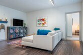 This well-appointed 2-bedroom, 3-bathroom residence in Madison, Wisconsin offers a thoughtfully designed single-floor layout with modern finishes throughout. The open-concept kitchen and living area serves as the heart of the home, featuring rich dark wood cabinetry, stainless steel appliances, a white subway tile backsplash, and a granite-topped island with bar seating illuminated by sleek pendant lighting. Hardwood-style flooring flows seamlessly through the main living areas, complementing the bright, neutral palette. The living room is generously sized with multiple windows that invite natural light and provide direct access to a private balcony. Both bedrooms are carpeted and comfortably proportioned, with the primary bedroom offering dedicated closet space and an en-suite bath. The primary bathroom features a double-sink vanity with granite countertops, warm wood cabinetry, a large framed mirror, and tile flooring. Additional bathrooms include a glass-enclosed shower. Two closets provide practical storage throughout the unit. The clean, contemporary aesthetic is consistent across all spaces, creating a cohesive and inviting atmosphere well-suited to everyday living in the heart of Madison.
