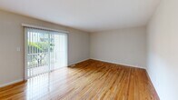 Located at 104 Robert Treat Dr in Milford, Connecticut, this well-maintained single-floor, 2-bedroom, 1-bathroom home offers a functional and comfortable layout with consistent hardwood flooring throughout. The open living room is bright and inviting, featuring sliding glass doors with vertical blinds that invite natural light and provide access to the outdoors. Adjacent to the living area, the dining room is defined by a stylish multi-bulb chandelier and a window overlooking the greenery outside. The kitchen is efficiently designed with white shaker cabinetry, dark granite countertops, tile flooring, and white appliances including a gas range, dishwasher, and refrigerator. A hallway with louvered double closet doors connects the main living areas to the bedrooms, providing ample storage. The spacious primary bedroom benefits from large windows framing leafy outdoor views, while the second bedroom is similarly bright and well-proportioned. The full bathroom is clean and neutral in tone, featuring tile flooring, a tub-shower combination with white tile surround, and a vanity with white countertop and brushed nickel fixtures. The overall aesthetic is light, clean, and move-in ready.