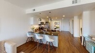 This thoughtfully designed single-floor residence offers a seamless blend of modern style and functional living. The open-concept kitchen serves as the heart of the home, featuring stainless steel appliances including a large side-by-side refrigerator, a microwave, and an electric range. Light wood-toned cabinetry pairs with dark granite countertops, while a spacious island with seating for three provides a natural gathering point beneath stylish pendant lighting. Rich hardwood flooring flows throughout the main living areas, adding warmth and continuity.

The living room is bright and welcoming, with natural light filtering through large windows and a curated selection of wall art lending a refined, relaxed atmosphere. A versatile flex room with carpet flooring, a ceiling fan, and contemporary décor offers potential as a home office or additional lounge space.

The primary bedroom is generously sized with soft carpeted floors, a bank of windows overlooking a green outdoor view, and a ceiling fan for comfort. Its en-suite bathroom includes a walk-in glass shower, hardwood floors, and access to a walk-in closet. A second bedroom offers a cozy, well-proportioned retreat, while the second bathroom features a tub-shower combination, granite vanity, and an illuminated mirror.