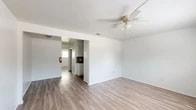 Located on SW 17th Ln in Gainesville, FL, this one-bedroom, one-bathroom residence offers a clean, functional layout across a single floor. Light-toned luxury vinyl plank flooring runs throughout, lending a cohesive and modern feel to the entire space. The open living area is bright and airy, featuring a ceiling fan with light fixture and smooth white walls that maximize the sense of openness. A wide entryway connects the living room to the kitchen, which stands out with dark granite countertops, a double-basin sink, white cabinetry, a mosaic tile backsplash, and white appliances including a range and refrigerator. The spacious bedroom accommodates generous furnishings and is filled with natural light from a large window with blinds, complemented by its own ceiling fan. A dedicated walk-in closet with dual hanging rods and shelving provides ample storage. The bathroom features a full tub-shower combination with marble-style wall surrounds and chrome fixtures. A hallway connects the main living areas efficiently, completing this practical and neatly designed Gainesville residence.